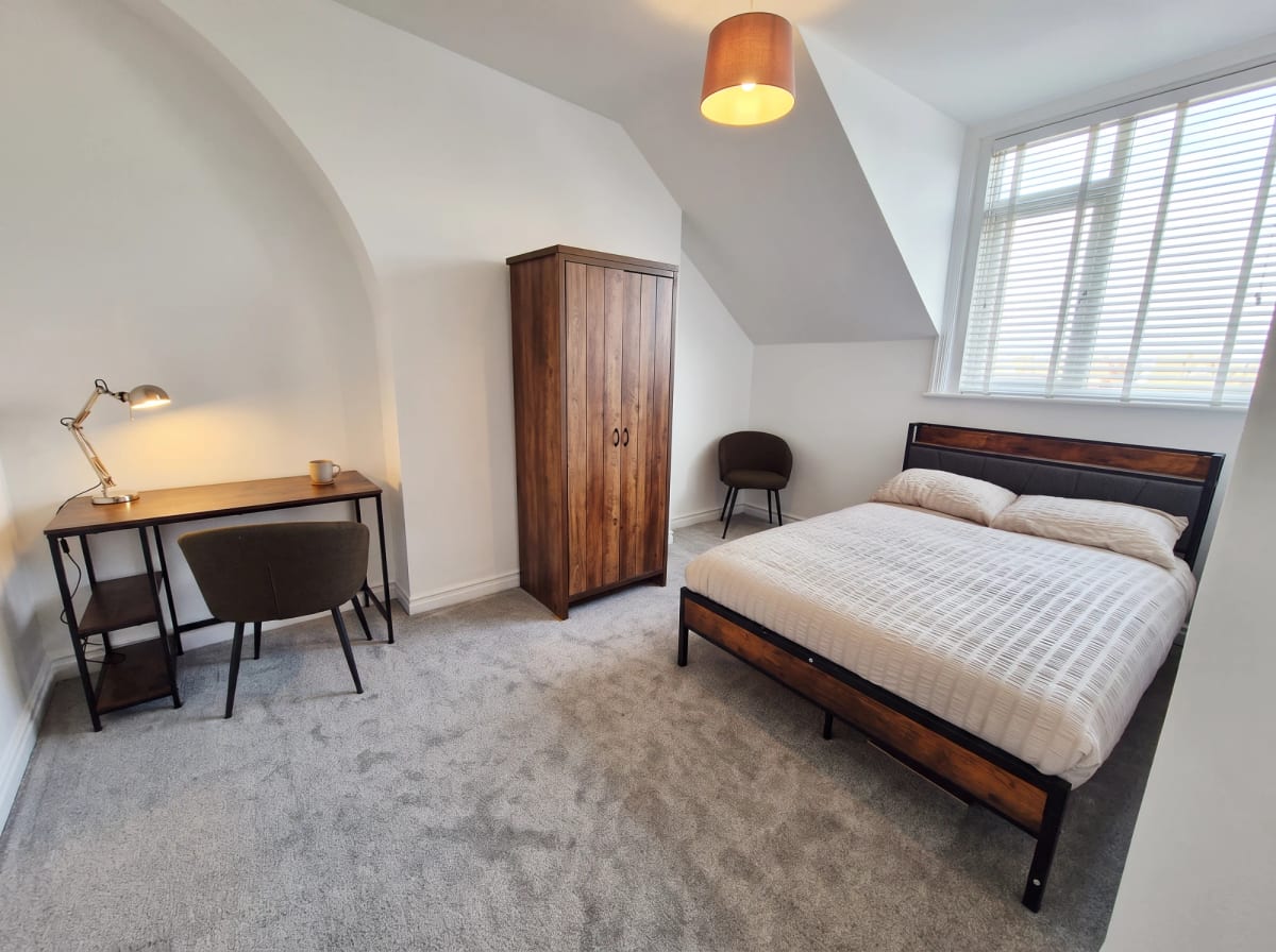 Furnished bedroom with a double bed, desk and wardrobe